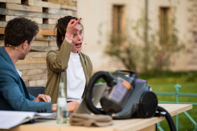 Eine Frau sitzt an einem Tisch und gestikuliert.