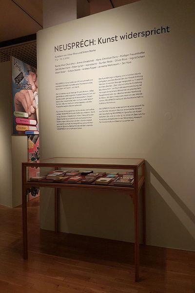 Eine Vitrine mit Büchern steht im Museum vor einem Wandtext